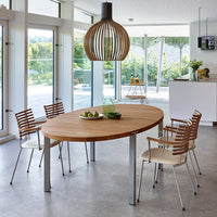A modern oval wooden dining table with a natural finish, complemented by light-colored chairs and a stylish pendant lamp.