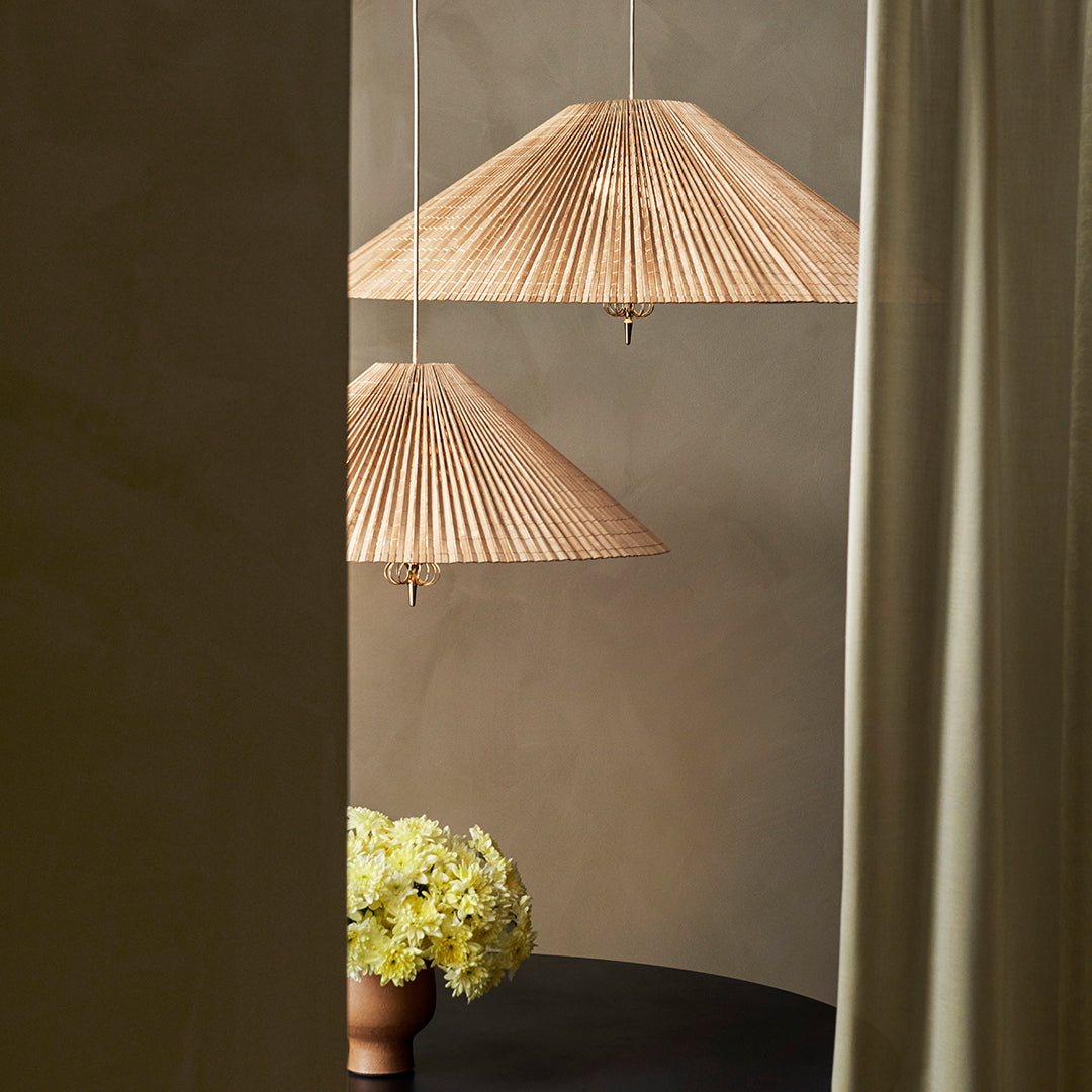 Natural woven pendant lamps with pleated shades in warm beige tones, set against a muted backdrop. 