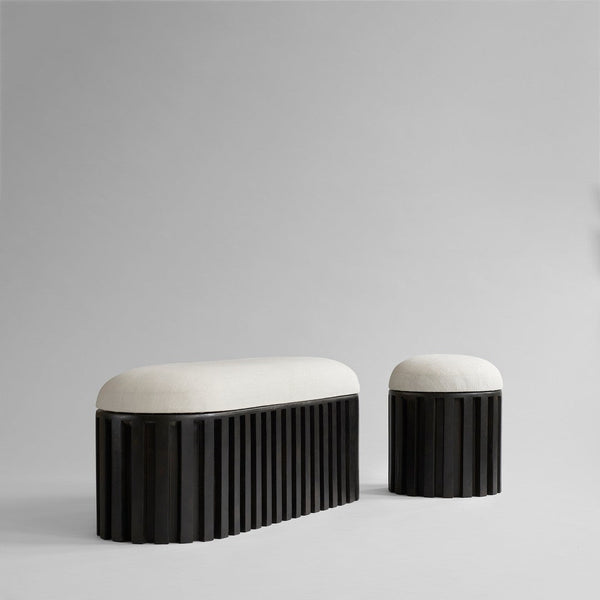 Black sculptural bench and stool with soft beige upholstery, featuring vertical ribbed patterns for a modern look.