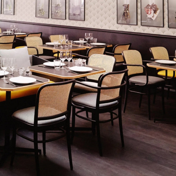 Elegant black and beige dining chairs with woven patterns, complemented by dark wood flooring and soft gray accents.