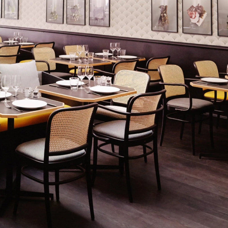 Elegant black and beige dining chairs with woven patterns, complemented by dark wood flooring and soft gray accents.