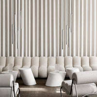 Modern living room with textured beige upholstery, white geometric tables, and a subtle gray-striped backdrop.