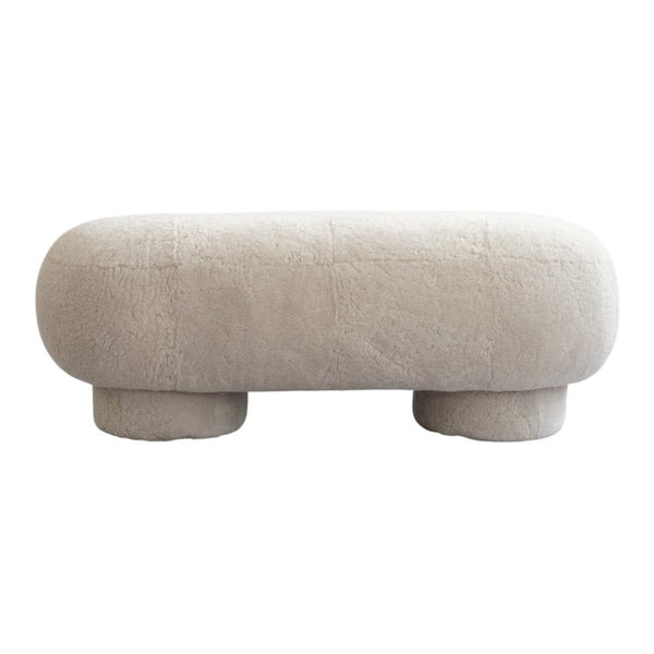 Soft beige upholstered ottoman with a textured, fluffy surface and rounded, minimalistic design.