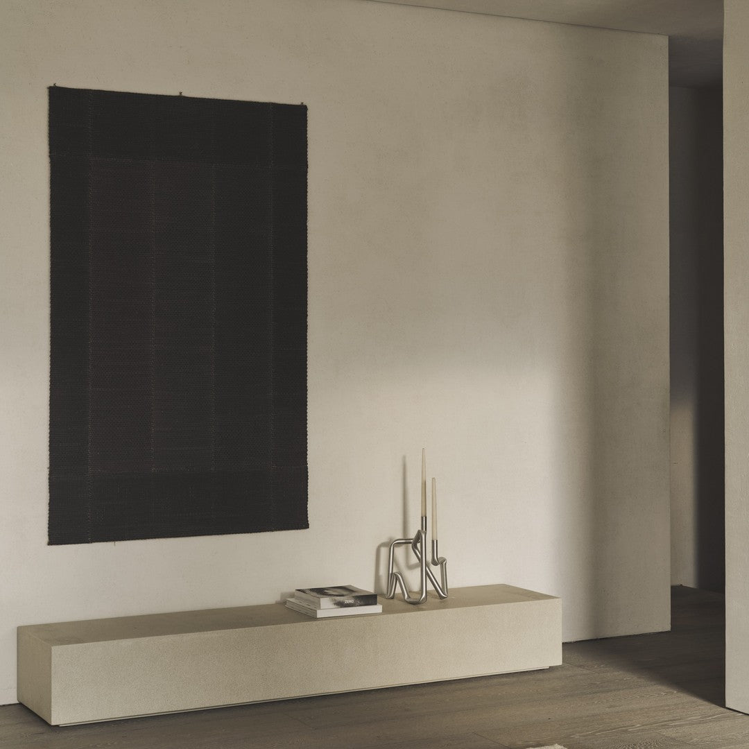 Black and dark maroon patterned wall hanging, adding rich texture to a minimalistic space.