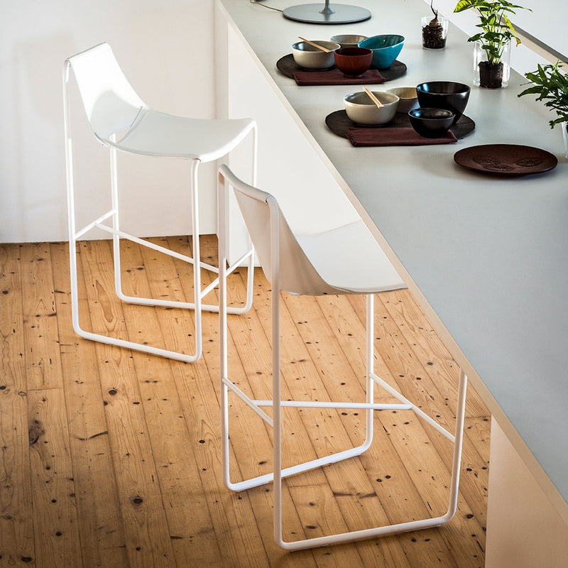 White modern bar stools with sleek design and geometric patterns, set against a natural wooden floor.