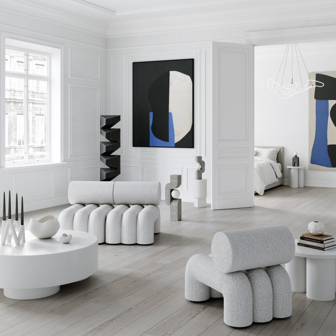 White sculptural furniture with gray tones and bold abstract black and blue wall art in a minimalist interior.