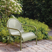 Green striped chair with a spiral pattern, set against lush greenery and cobblestone. Ideal for outdoor decor.