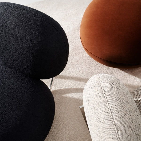 Black, brown, and light gray textured poufs on a soft beige surface, creating a modern color contrast.