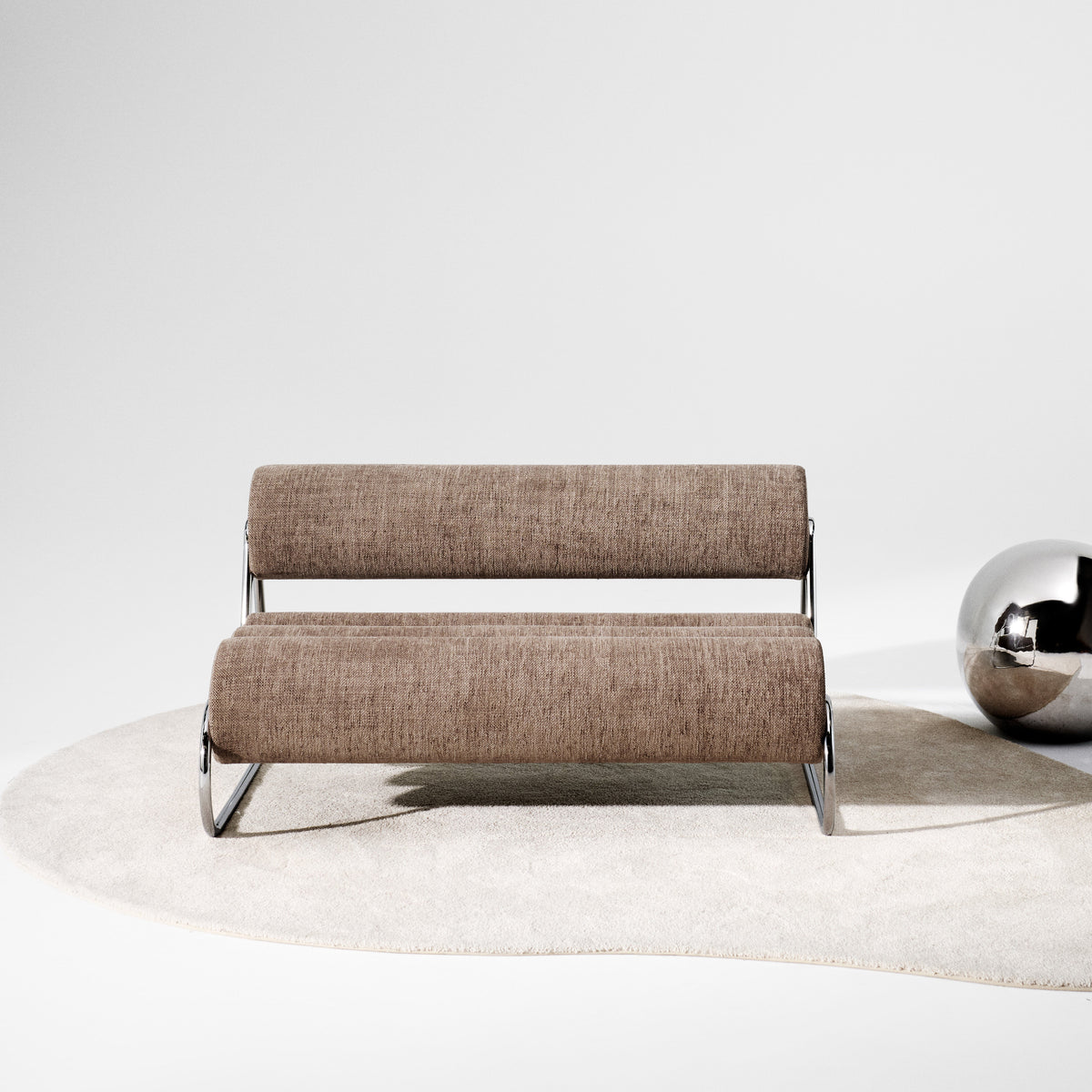 Brown textured sofa on a soft beige rug, paired with a shiny silver accent ball.