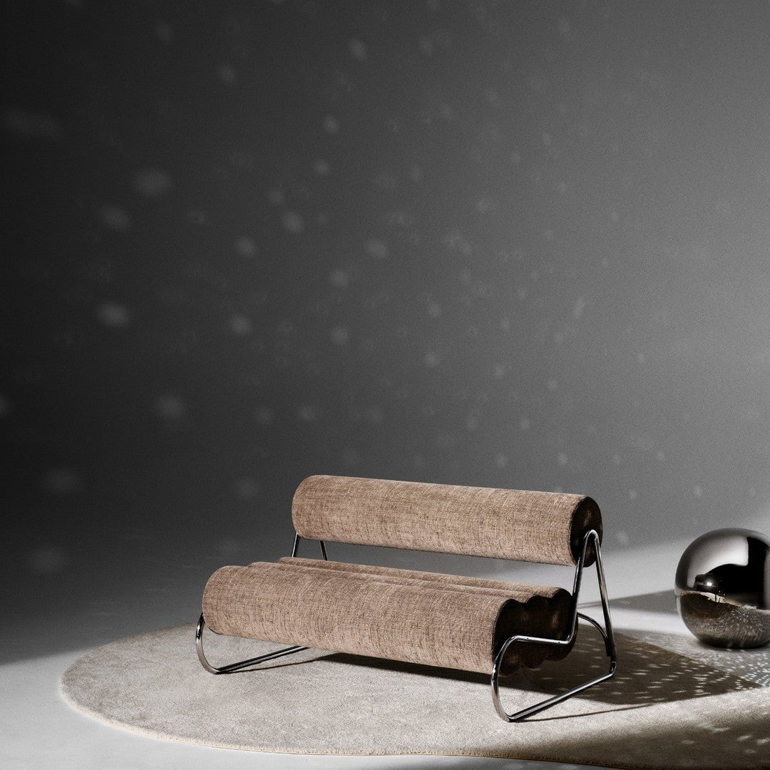 Brown woven fabric sofa on a soft gray rug with a sleek chrome frame against a dark backdrop.