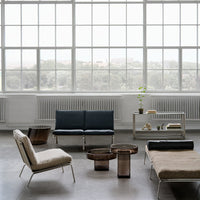 Modern furniture arrangement featuring dark blue, soft beige, and metallic bronze accents against a bright, airy backdrop.
