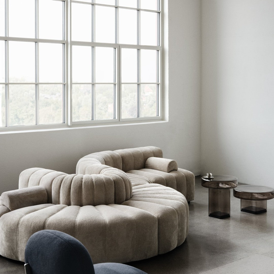 Beige, plush sectional sofa with rounded patterns; modern design enhances minimalistic decor.