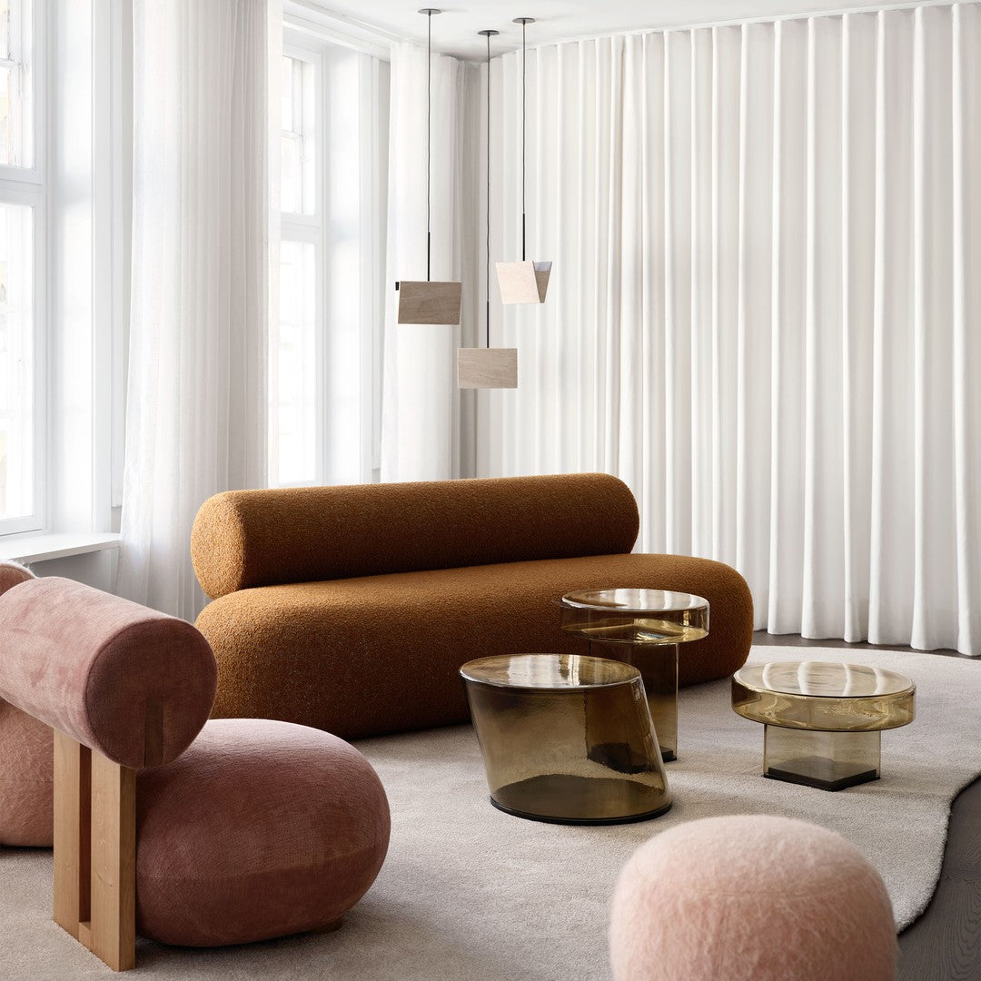 Warm brown sofa, soft pink accents, and sleek glass tables enhance this modern, neutral-toned living space.