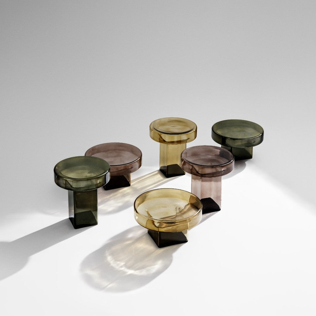 Set of five glass tables in hues of green, brown, and amber with sleek geometric patterns.