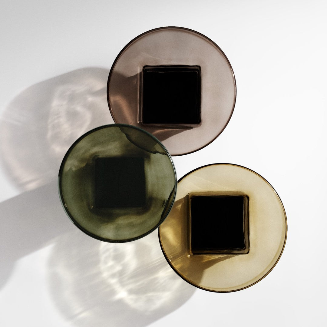 Three decorative glasses in smoky brown, green, and amber with square bases, showcasing elegant color transparency.