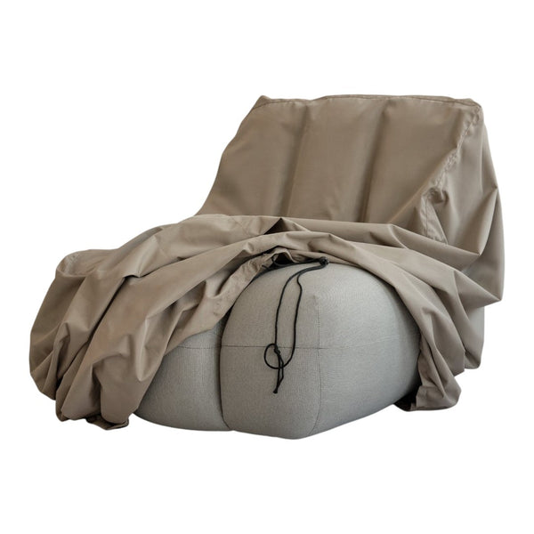Beige cozy chair with soft taupe throw blanket, featuring smooth textures and understated elegance in neutral tones.