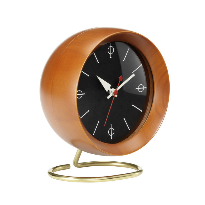 Mid-century modern clock in rich wood tones with a black face and white markings, accented by red hands and a gold base.
