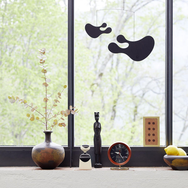 Black abstract wall decor against a natural backdrop, complemented by earthy shades and minimalist decor elements.