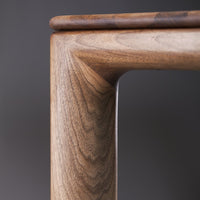 Warm walnut wood grain with subtle dark brown tones, highlighting a smooth, polished finish and elegant angles.