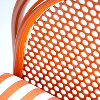 Close-up of an orange perforated chair back with bold orange and white striped cushion pattern.