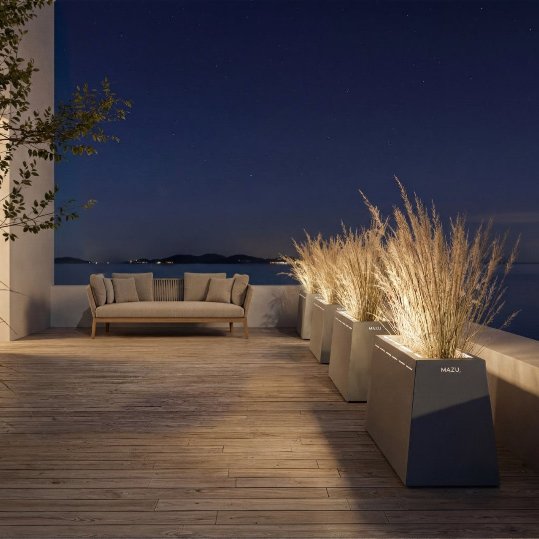 "Contemporary outdoor setting with gray planters and muted beige couch, illuminated by soft ambient lighting."