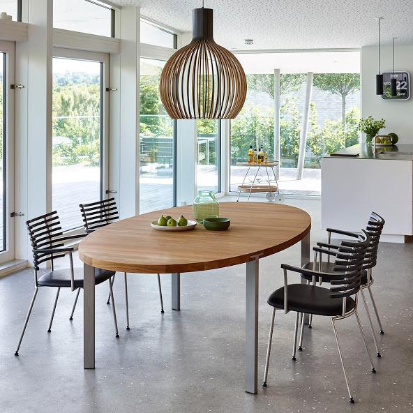 "Modern wood dining table with silver metal legs, surrounded by black striped chairs and accented by a wooden pendant light."