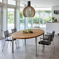 "Modern wood dining table with silver metal legs, surrounded by black striped chairs and accented by a wooden pendant light."