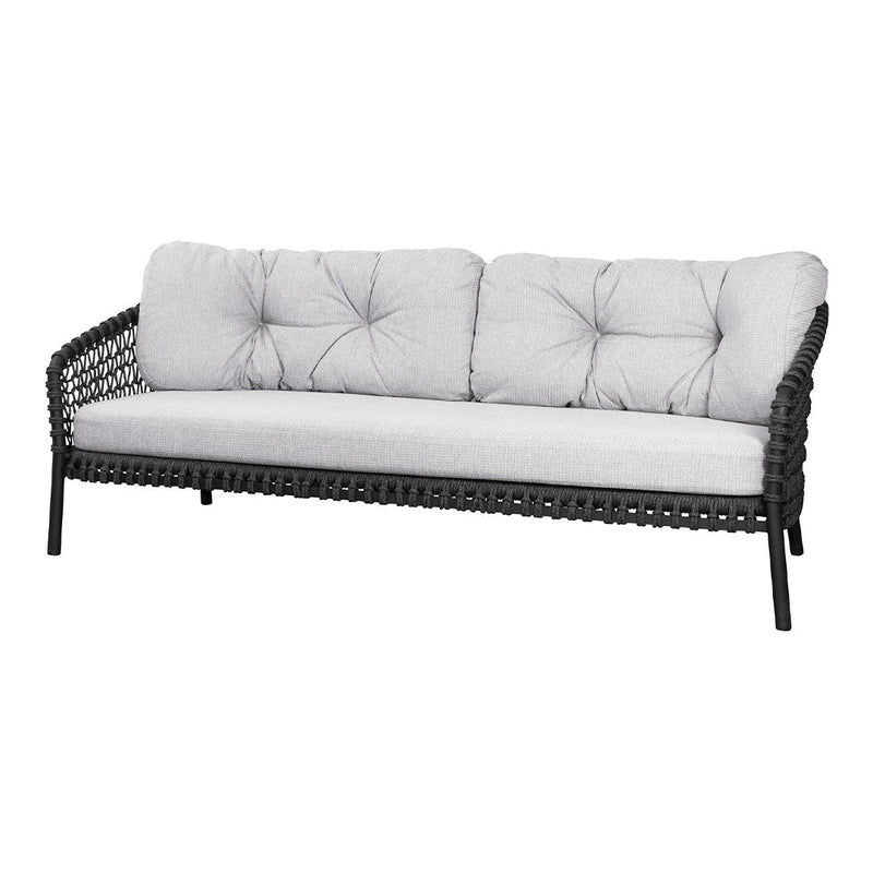 Stylish black woven outdoor sofa with soft gray cushions and tufted design for modern decor.