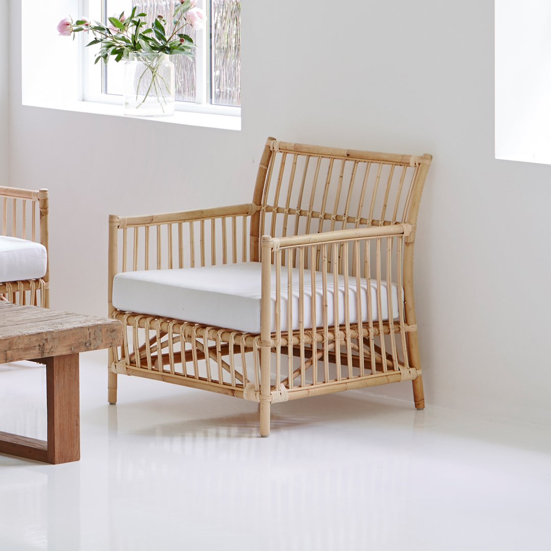 Natural bamboo chair with a neutral white cushion, featuring an open slat pattern for a modern aesthetic.