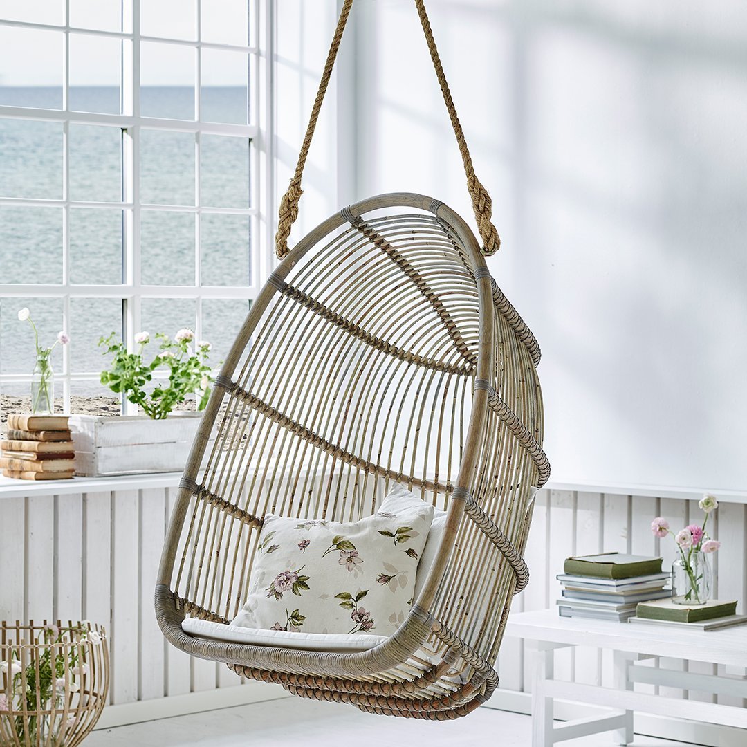 Hanging rattan chair with a natural finish and floral patterned cushion, perfect for stylish home decor.