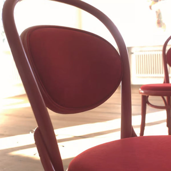 "Elegant red chair with smooth curves and a textured, rounded backrest, ideal for modern interiors."