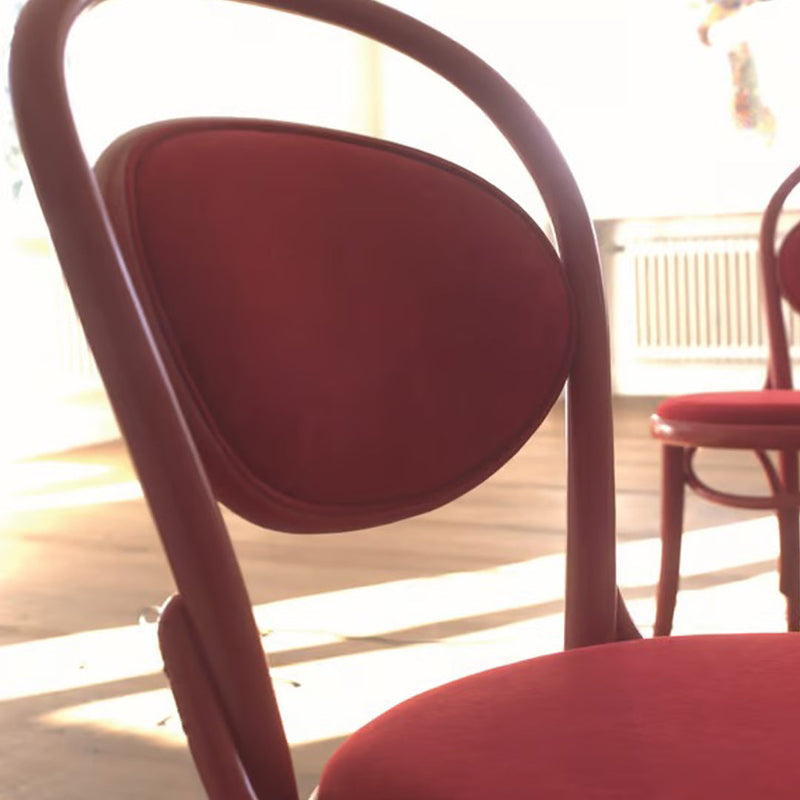 "Elegant red chair with smooth curves and a textured, rounded backrest, ideal for modern interiors."