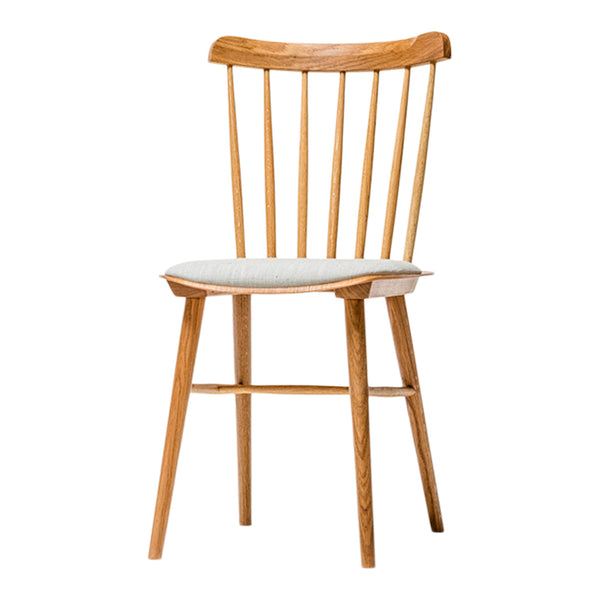 Light wood dining chair with vertical spindles and a cream cushion, showcasing a minimalist design and neutral colors.