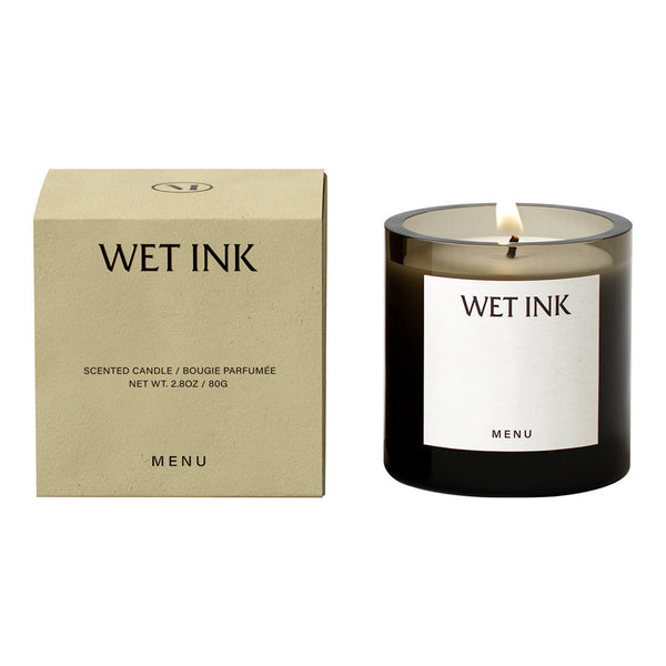 Sleek black candle with warm amber glass and minimalist beige packaging featuring black text.
