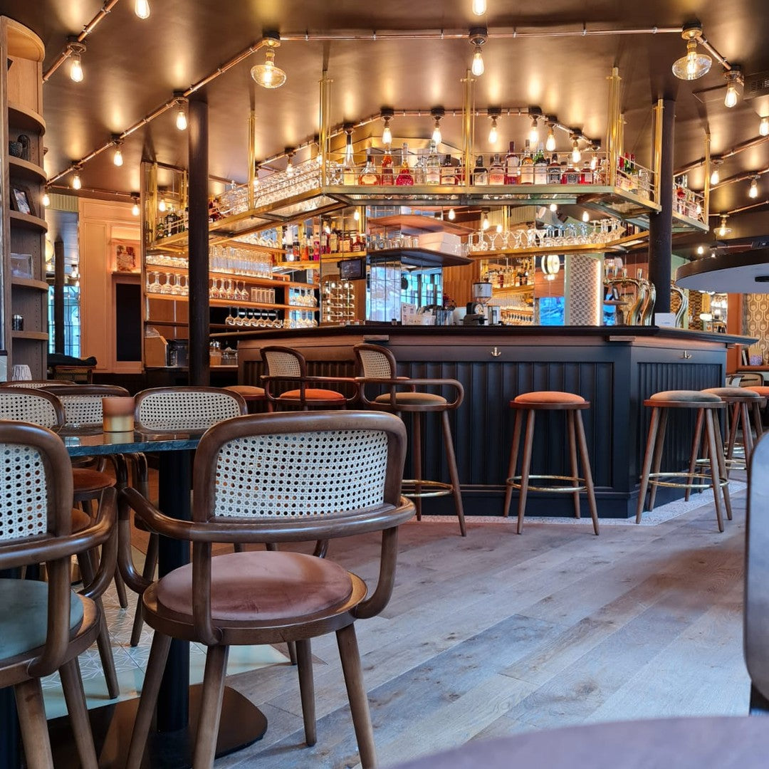 Cozy cafe interior featuring warm wood tones, rattan accents, and soft lighting with a modern bar setup.