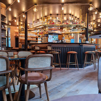 Cozy cafe interior featuring warm wood tones, rattan accents, and soft lighting with a modern bar setup.