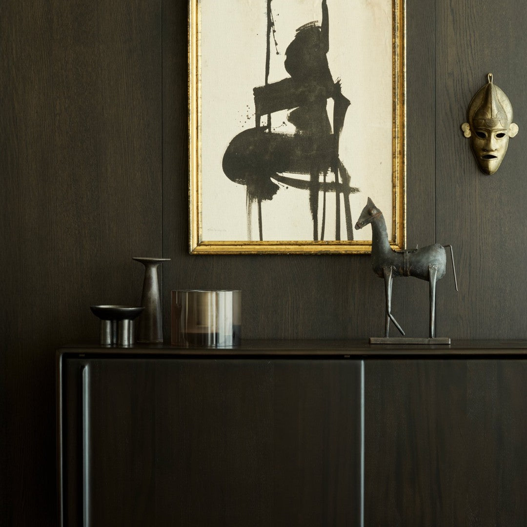 Black and gold accents with earthy tones, featuring a bold abstract artwork and sleek metallic decor.