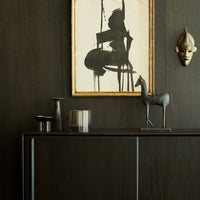 Black and gold accents with earthy tones, featuring a bold abstract artwork and sleek metallic decor.