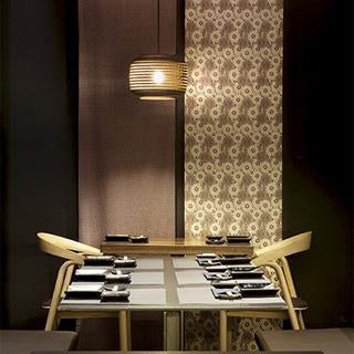 Elegant dining setup with a chic black and gold color scheme, featuring floral patterned wallpaper and minimalist tableware.