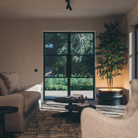 Cozy living room featuring neutral beige tones, textured fabrics, and natural green plant accents.