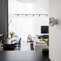 Modern living room featuring neutral tones, soft pink accents, and sleek black furniture with minimalist patterns.