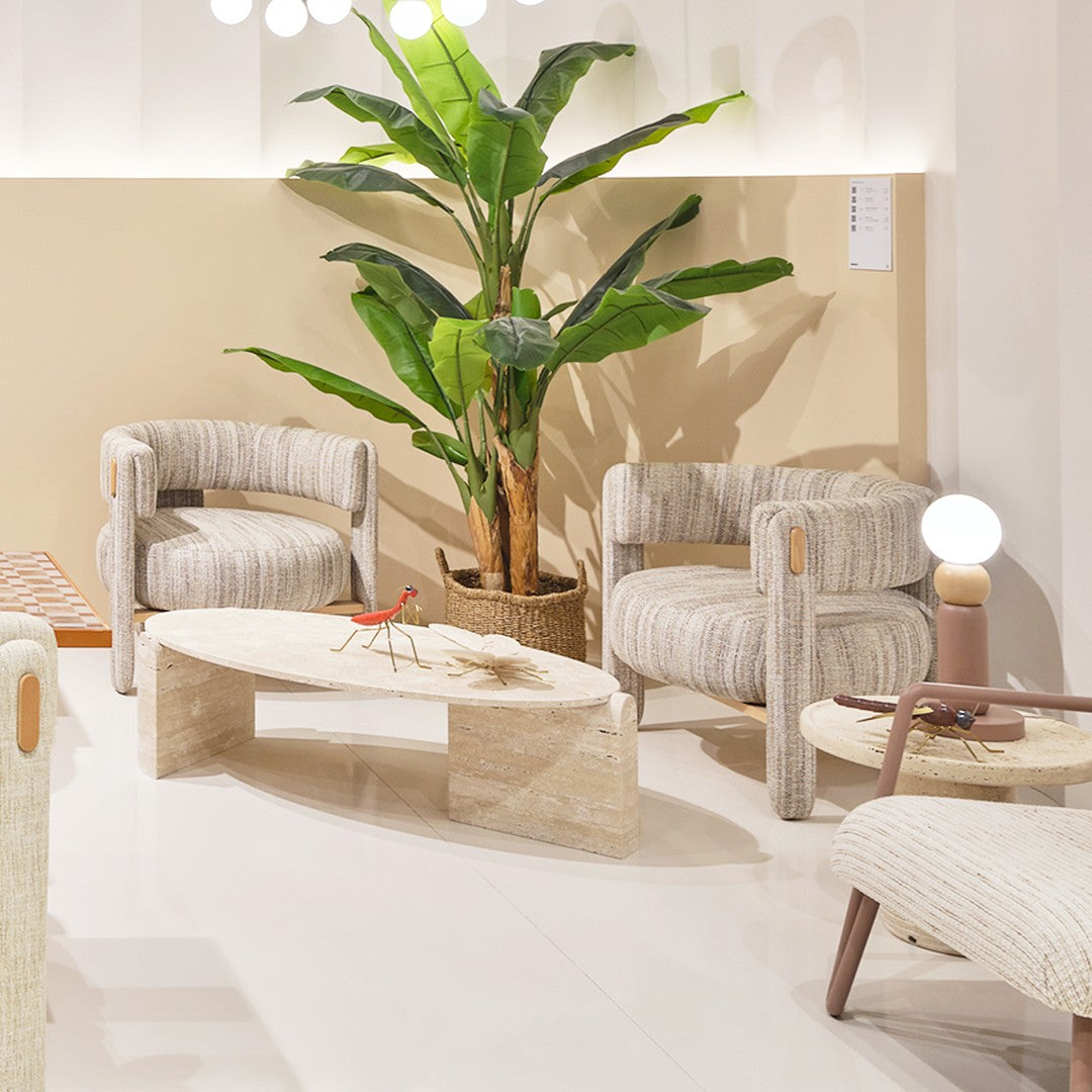 Textured beige and cream chairs with striped patterns, light wooden table, and vibrant green plant in a bright, airy space.
