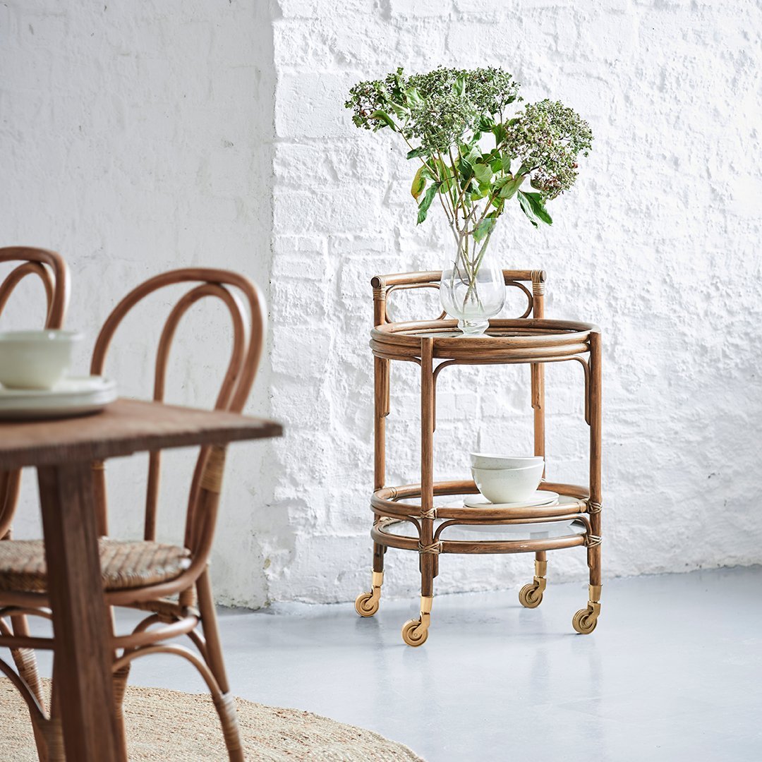 Natural rattan serving cart with a light wood finish, featuring a circular top and patterned design. White background enhances elegance.