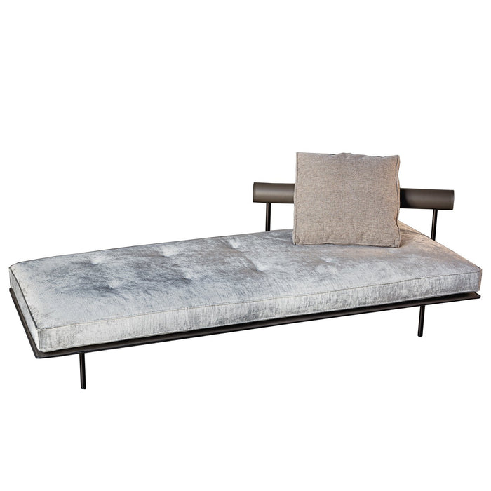 Gray velvet daybed with a sleek black metal frame and a textured beige accent pillow. Simple, modern design.