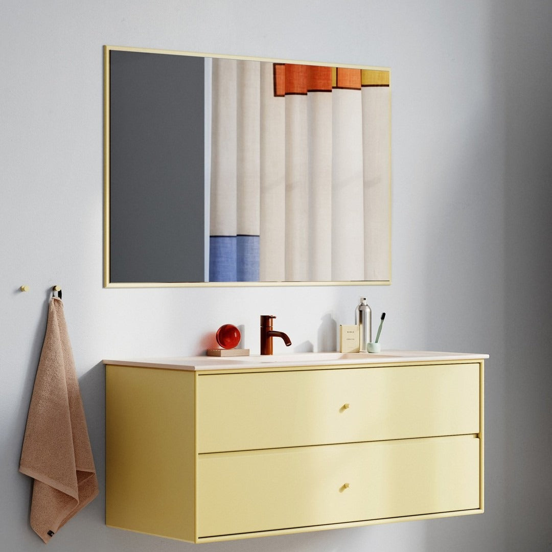 Modern bathroom vanity in soft yellow with minimalist design, featuring gray, orange, and blue striped patterns in the mirror.