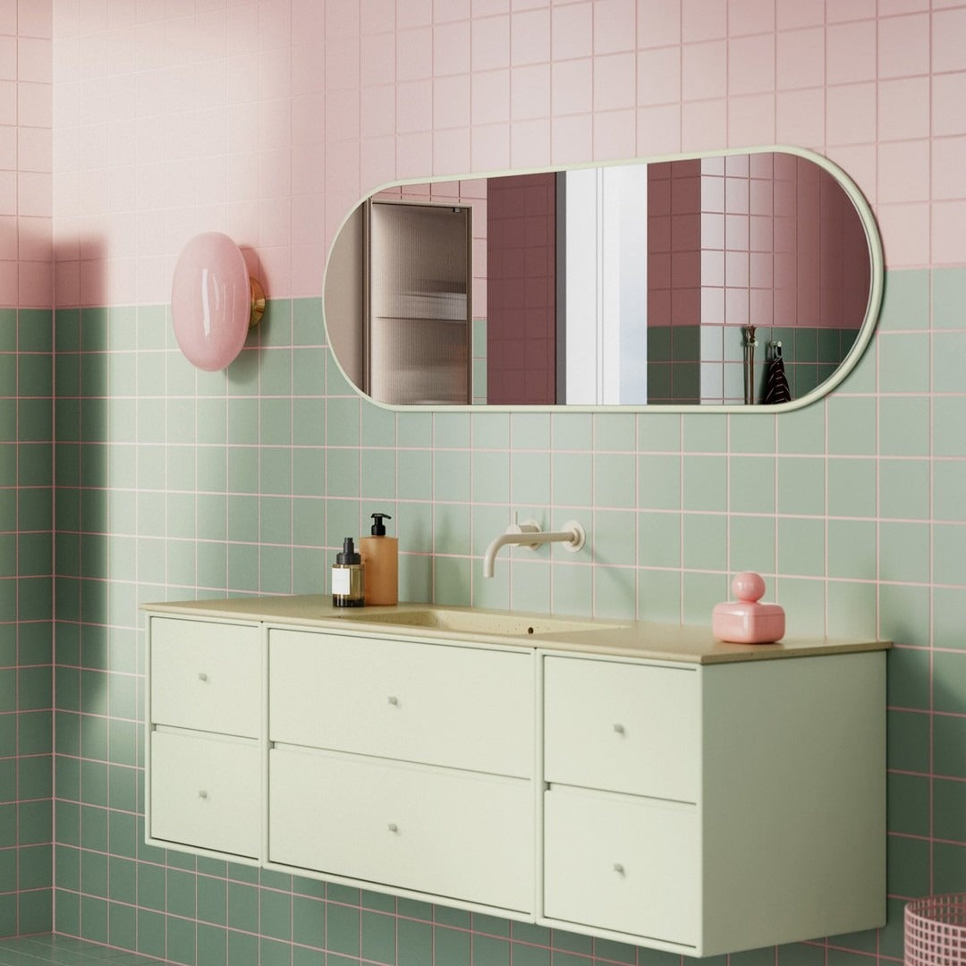 Mint green cabinet with pastel pink and maroon walls, featuring geometric patterns and a sleek oval mirror.
