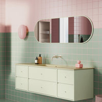 Mint green cabinet with pastel pink and maroon walls, featuring geometric patterns and a sleek oval mirror.