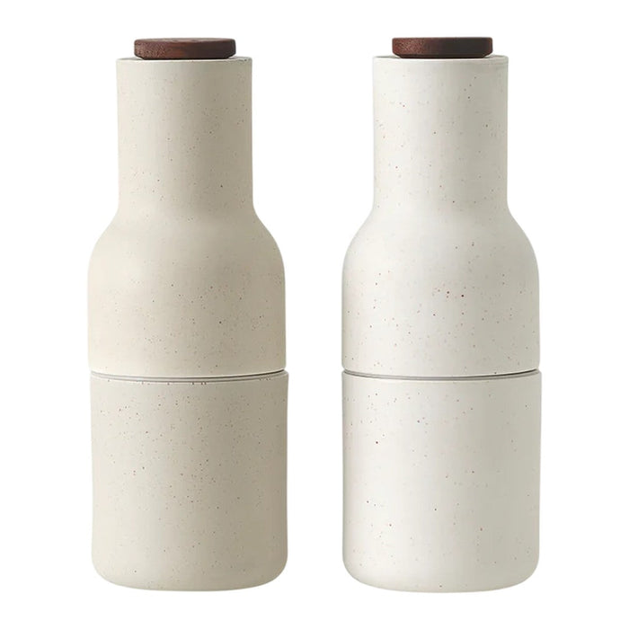 Neutral beige ceramic salt and pepper shakers with smooth textures and natural wooden tops.