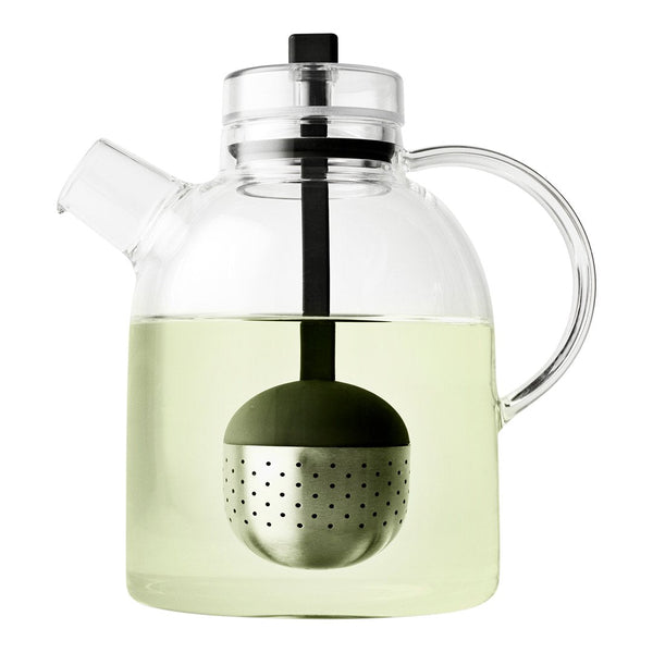 Clear glass teapot with a stainless steel infuser, featuring a minimalist design and soft green tea inside.