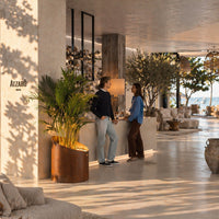 Modern interior featuring neutral tones, warm wood accents, lush greenery, and textured decor elements.